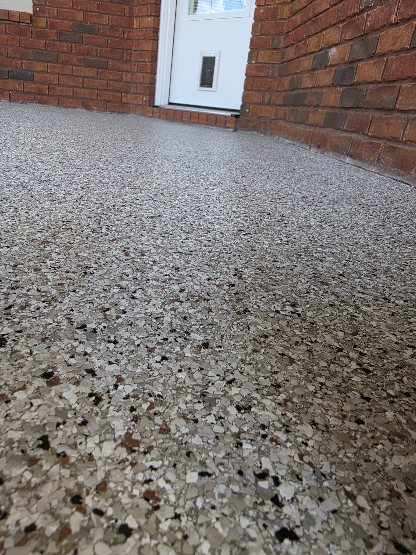 Low angle detail of the gray flake coating beside a brick home's entry door