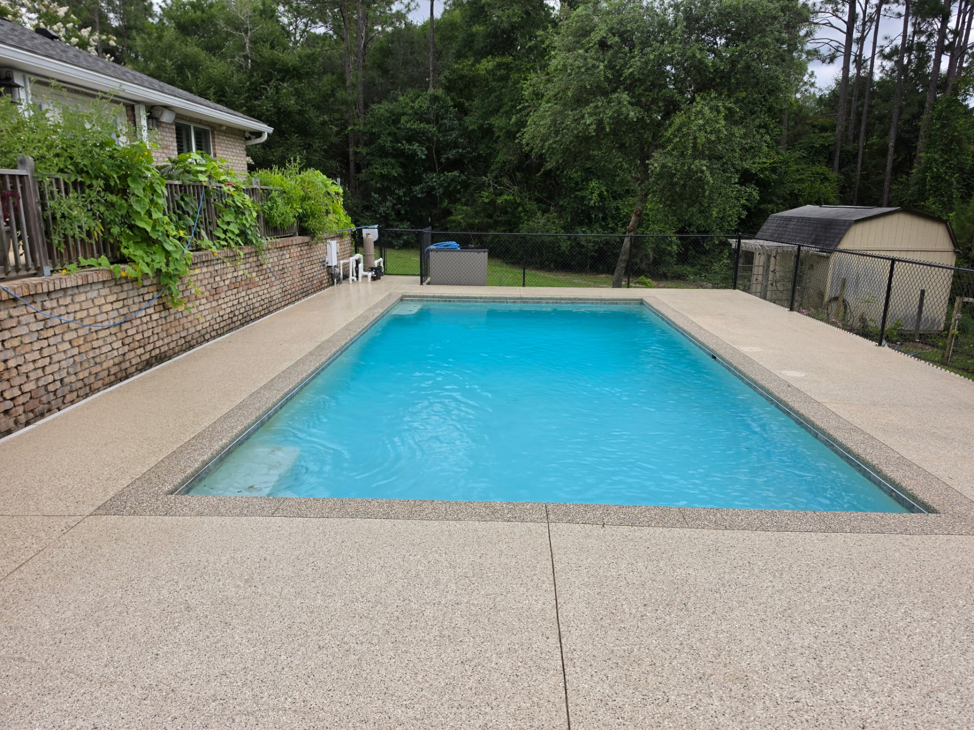 Finished flake-coated pool deck beside a brick wall and fence