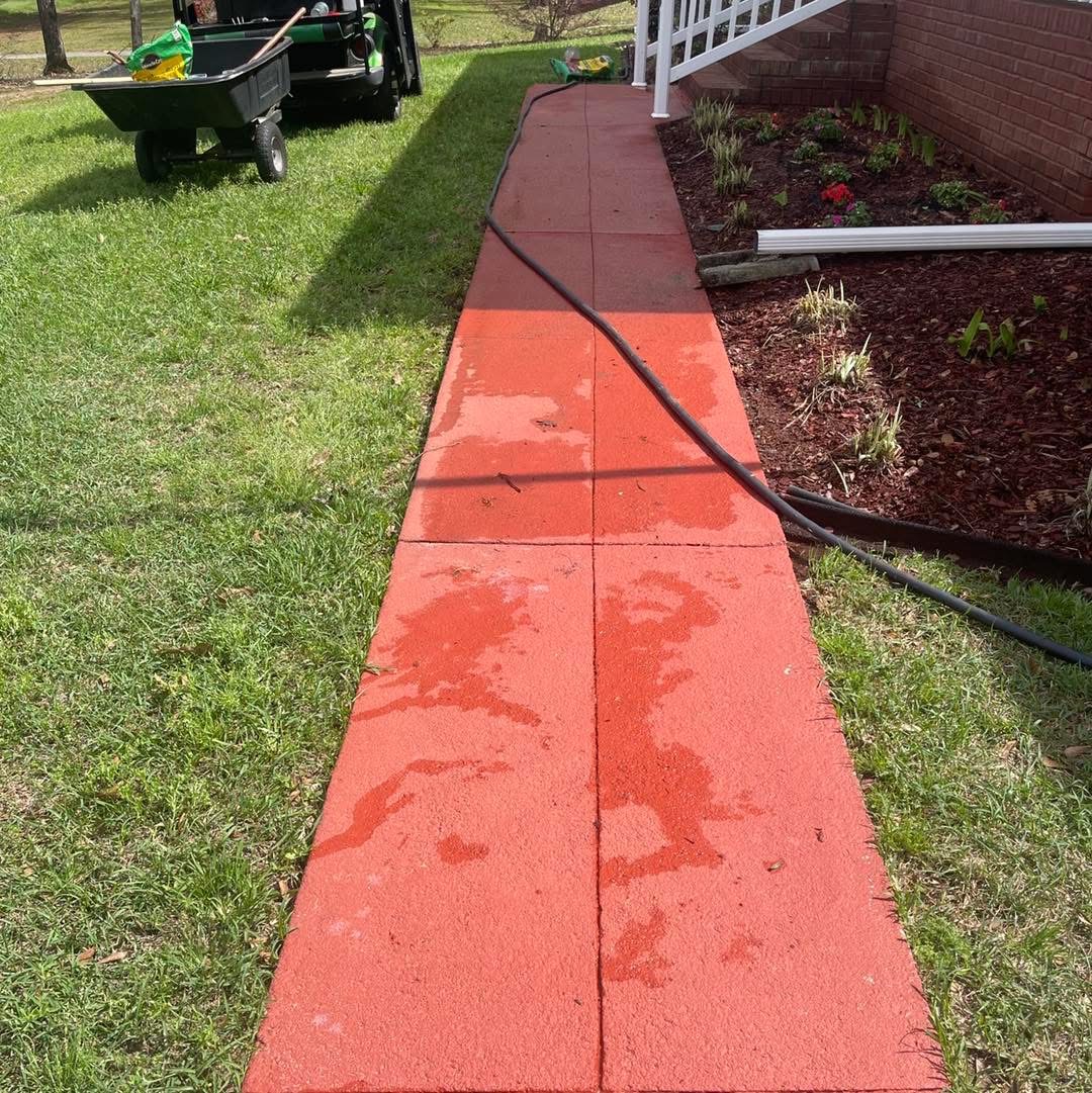 Before: peeling orange paint on a concrete walkway between lawn and garden bed