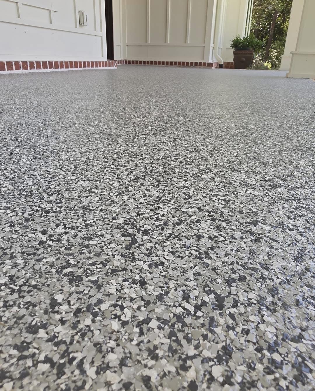 Close-up of black, white, and gray flake coating on a porch floor