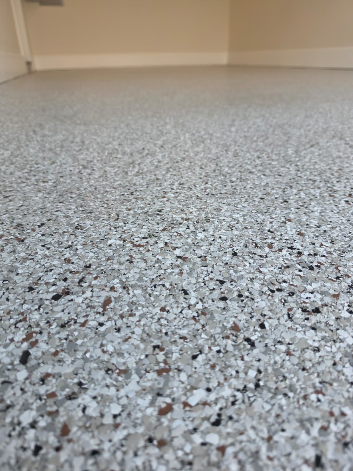 Close-up detail of gray, white, and black flake blend on a garage floor