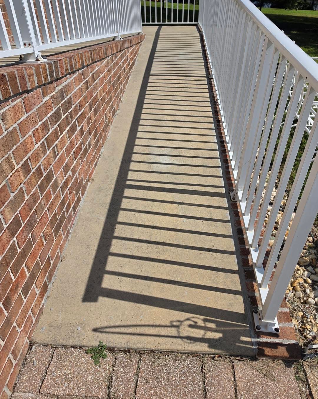 Before: stained concrete walkway with weeds along the brick border, seen from above