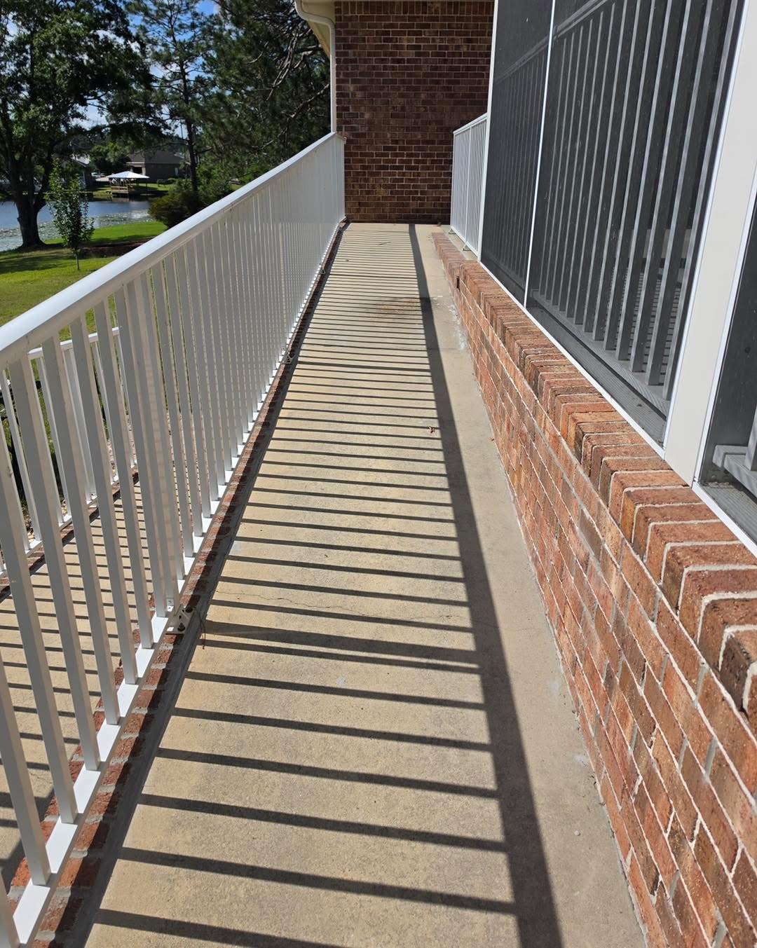 Before: weathered concrete walkway beside a white railing and brick wall, looking toward the lake