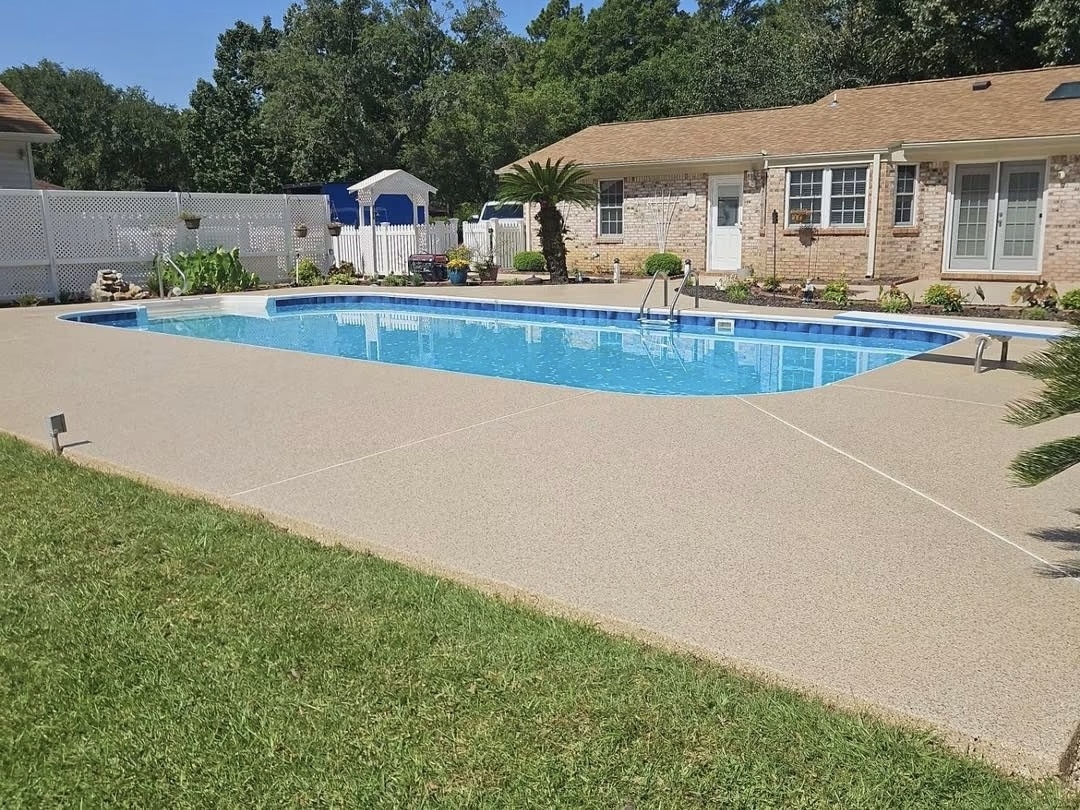 Backyard pool deck with a freshly installed tan flake concrete coating surrounding a blue swimming pool